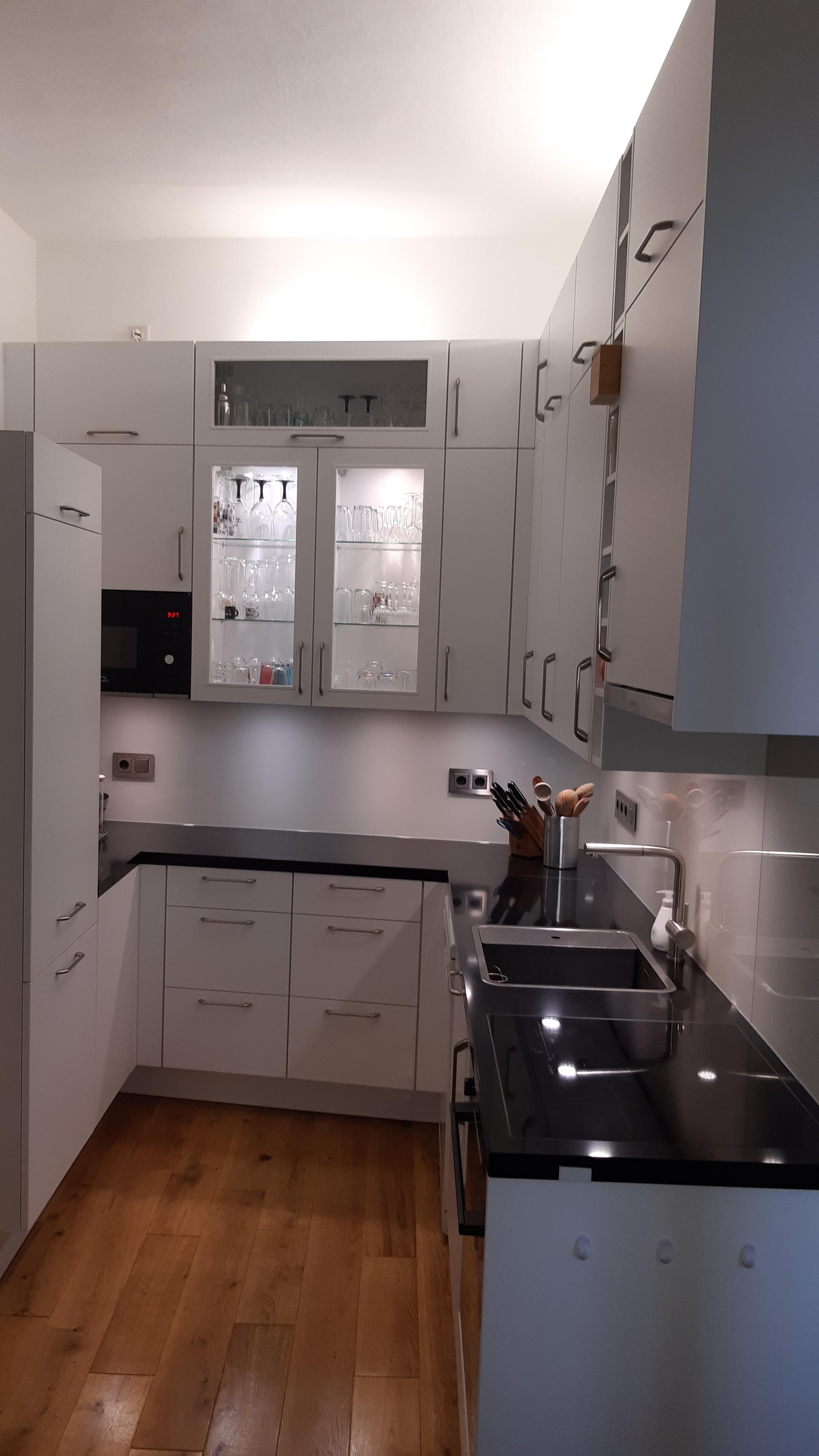 Küche_von_Leicht_mit_weißen_und_blauen_Küchenfronten_mit_Glasvitrine_beleuchtet