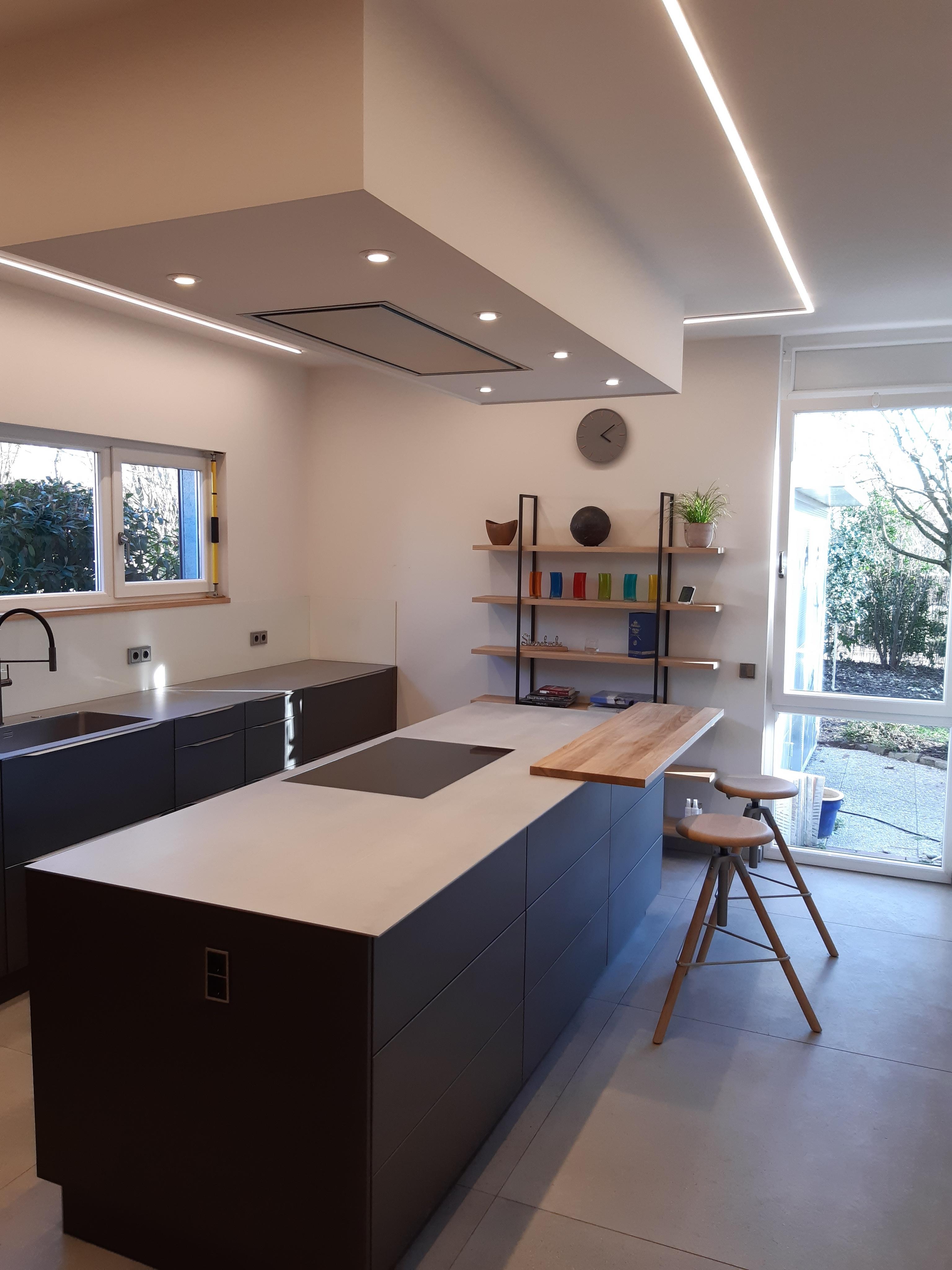 Leicht-Küche_mit_dominanter_Kücheninsel_und_Regal